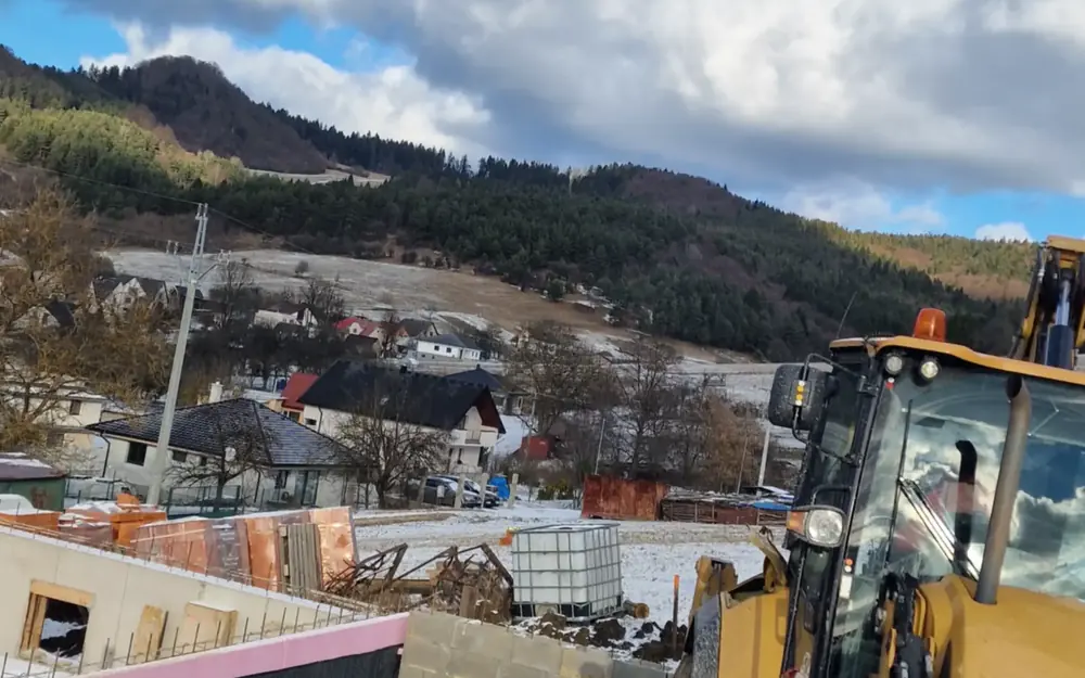 Construction machine above a village below the mountains